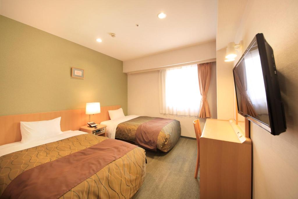 a hotel room with two beds and a flat screen tv at Hotel Grand City in Tokyo