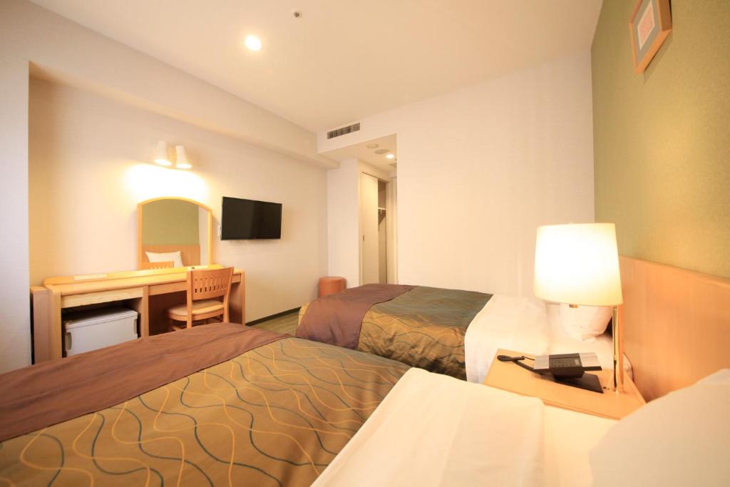 a hotel room with two beds and a desk at Hotel Grand City in Tokyo
