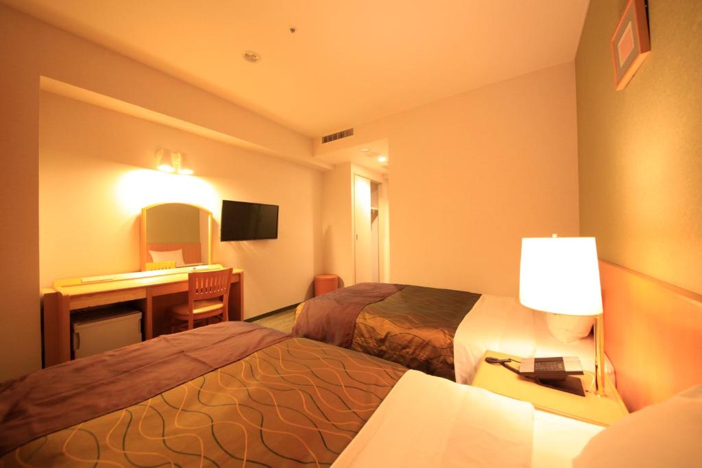a hotel room with two beds and a desk at Hotel Grand City in Tokyo