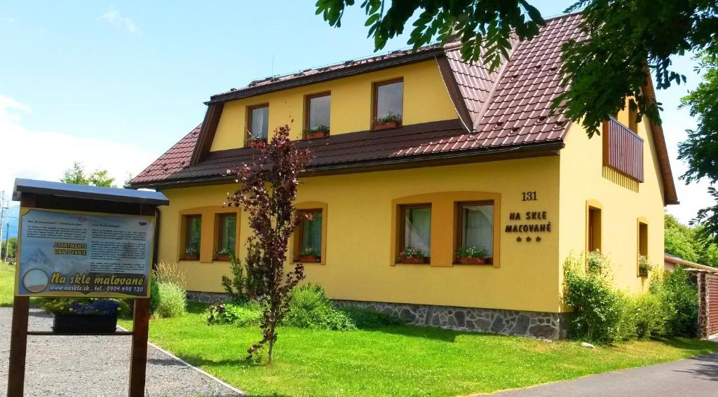 a yellow house with a sign in front of it at Apartmany Na Skle Malovane in Liptovská Kokava