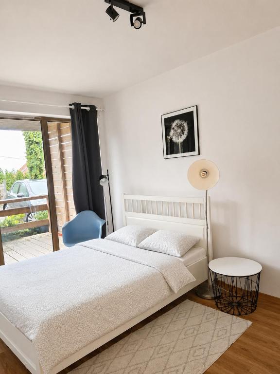 a white bedroom with a bed and a blue chair at Apartament na Wzgórzu in Wieliczka