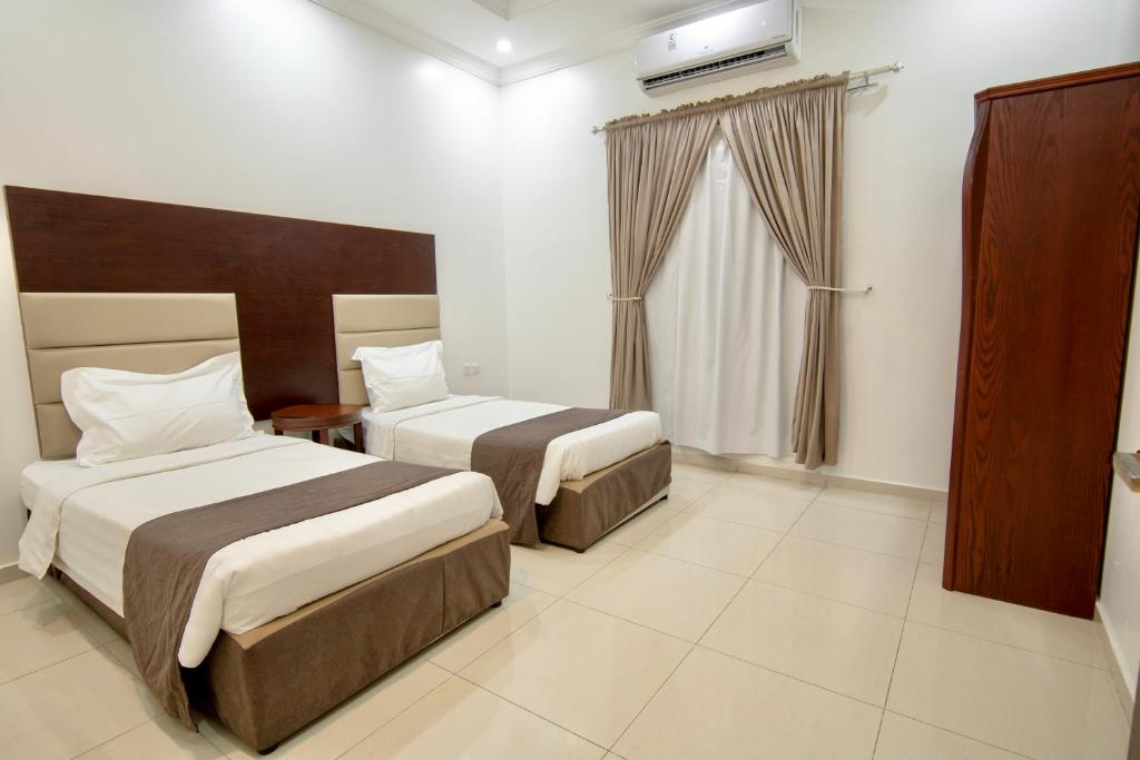 a hotel room with two beds and a television at شقق راف التميز in Umm Salam