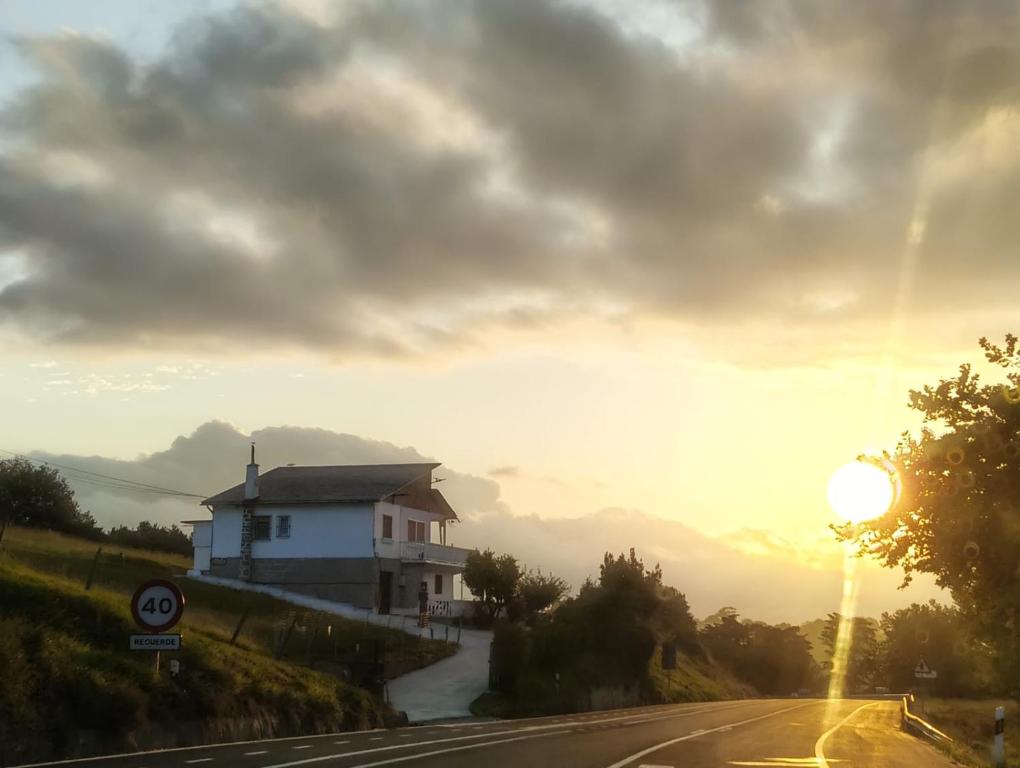 a house on the side of a road with the sunset at Apartamentos Santillán in San Vicente de la Barquera