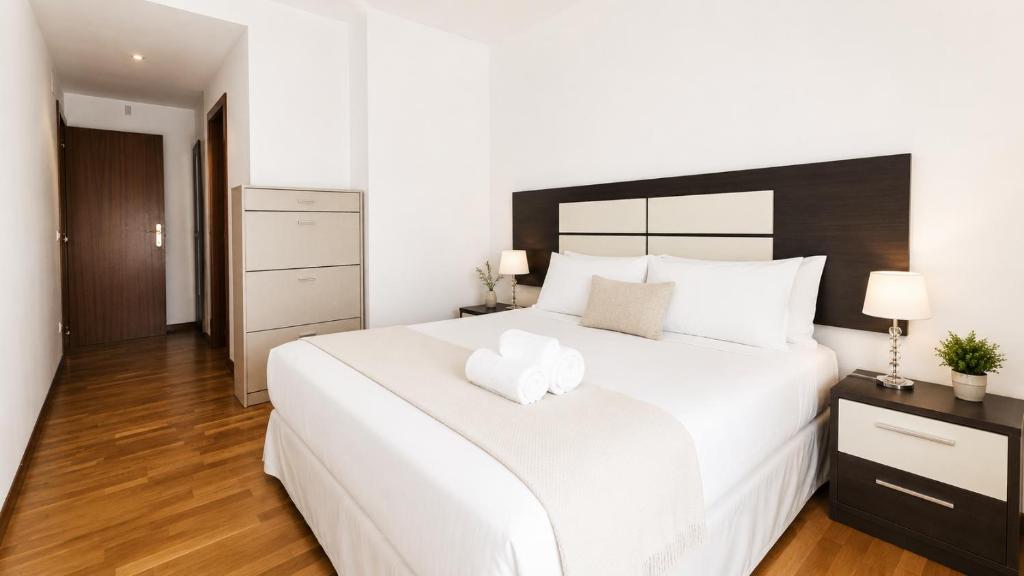 a bedroom with a large white bed with a black headboard at Apartamento Golf Rioja Alta in Cirueña