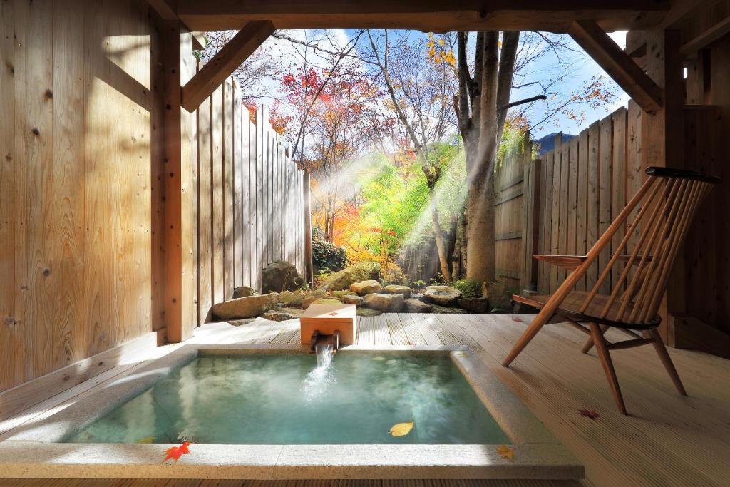 a hot tub in a backyard with a swing and a chair at Syoubun in Minakami