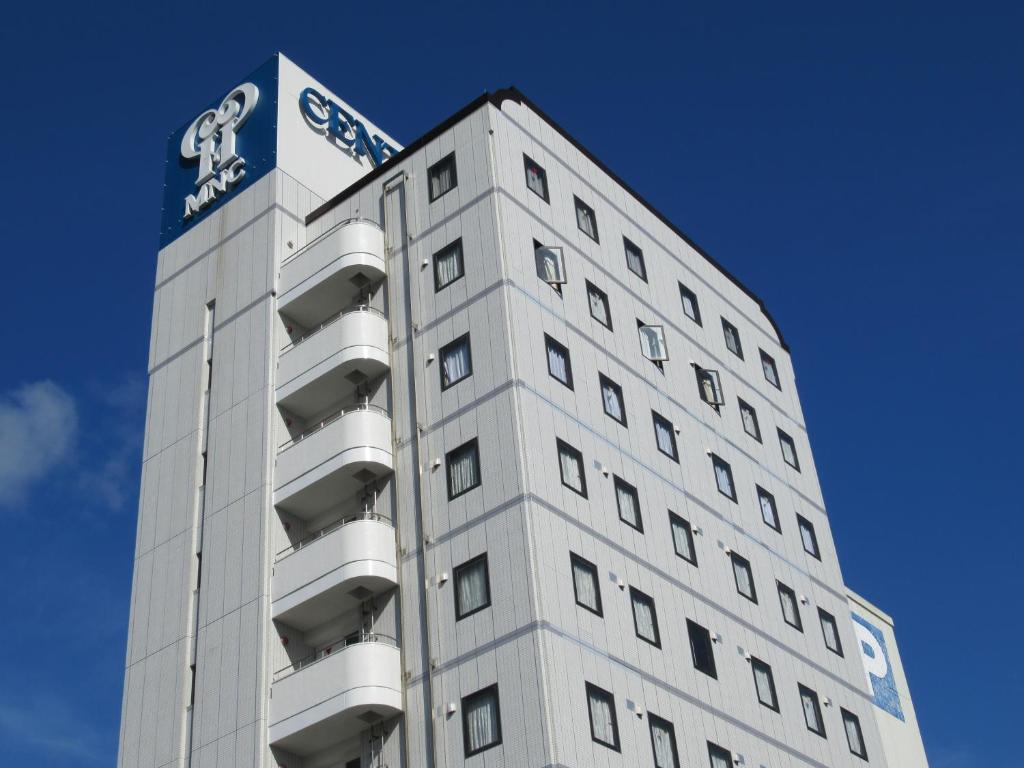 a tall white building with a sign on top of it at Center Hotel Mihara in Mihara