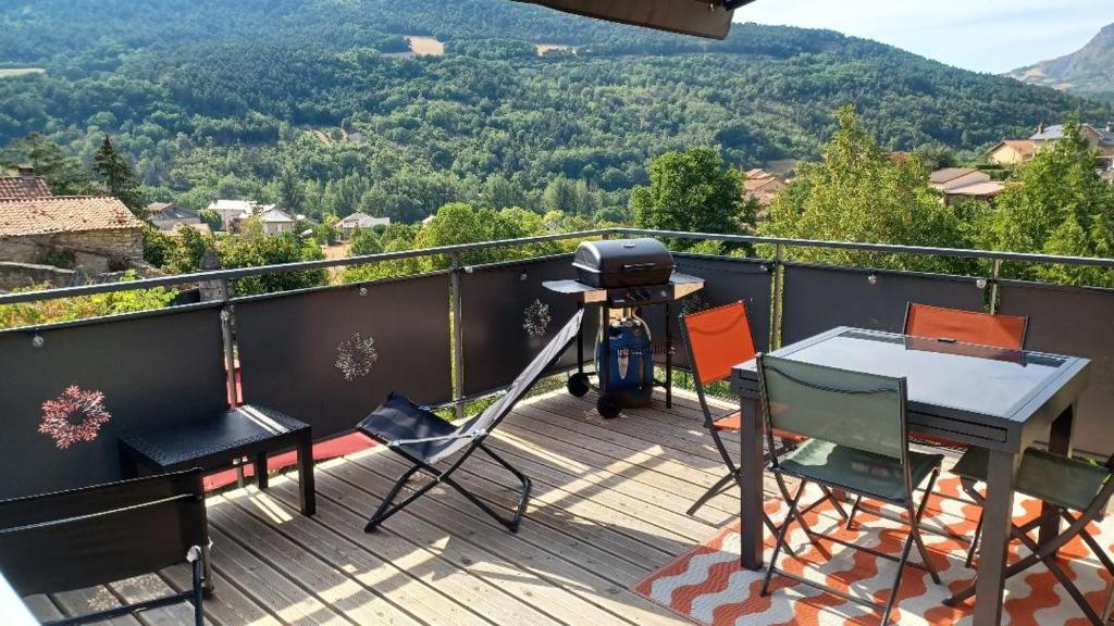 a grill on a deck with a table and chairs at Le Temps des Cerises in La Cresse