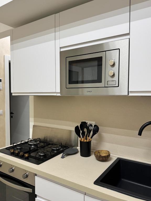a kitchen with a stove and a microwave at Casa Vittoria - Moderno bilocale a pochi passi dal mare in Galatone