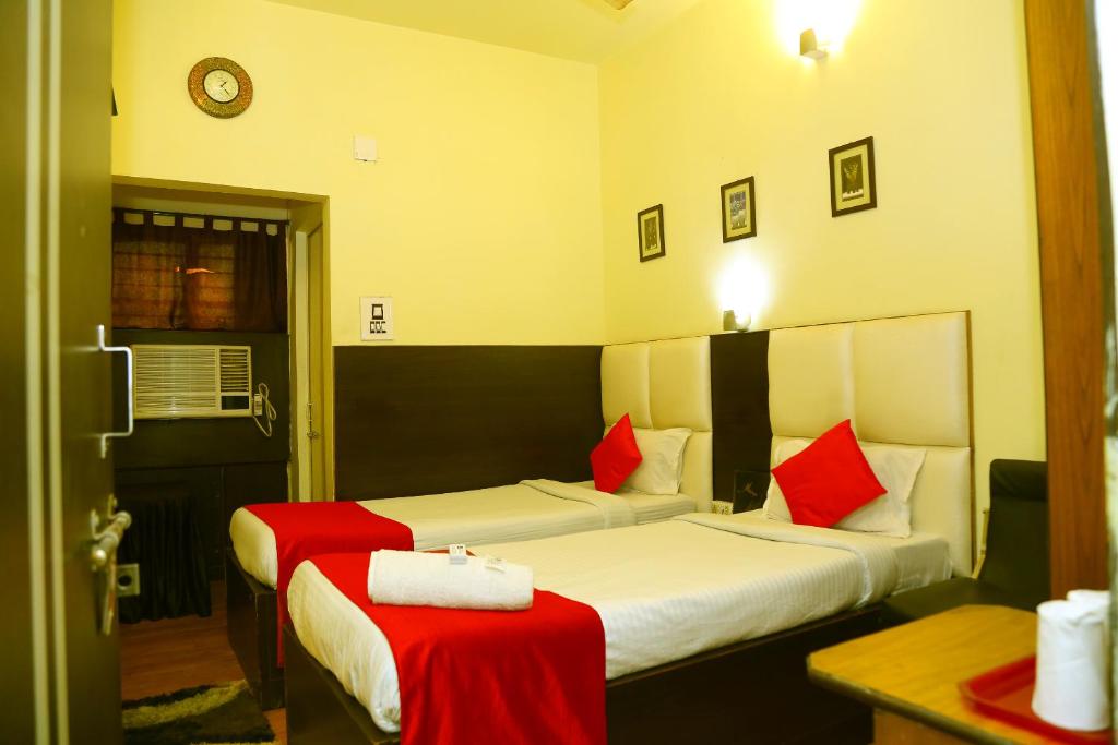 ein Hotelzimmer mit 2 Betten und roten Kissen in der Unterkunft Hotel Holideiinn in Jamshedpur