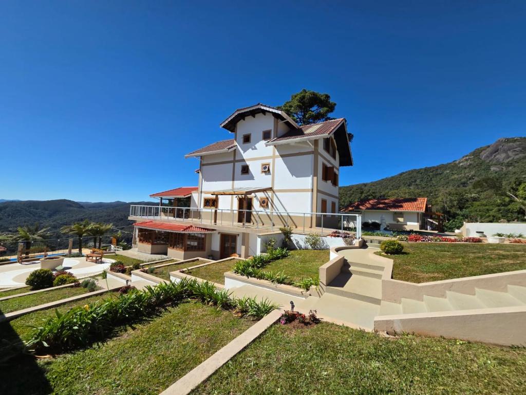 a large white building with a hill in the background at The Winter Mountain Hotel in Monte Verde