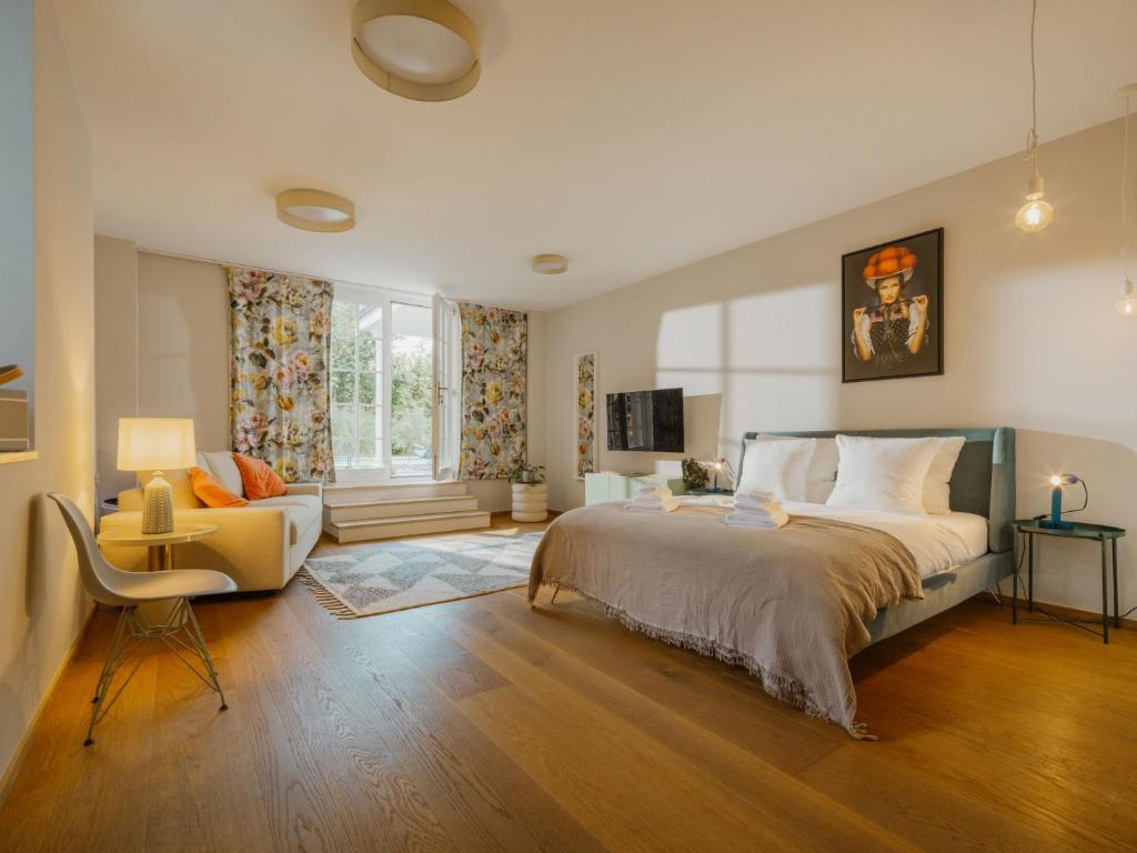 a bedroom with a large bed and a chair at Boutique Apartments Freiburg - Elsa in Freiburg im Breisgau