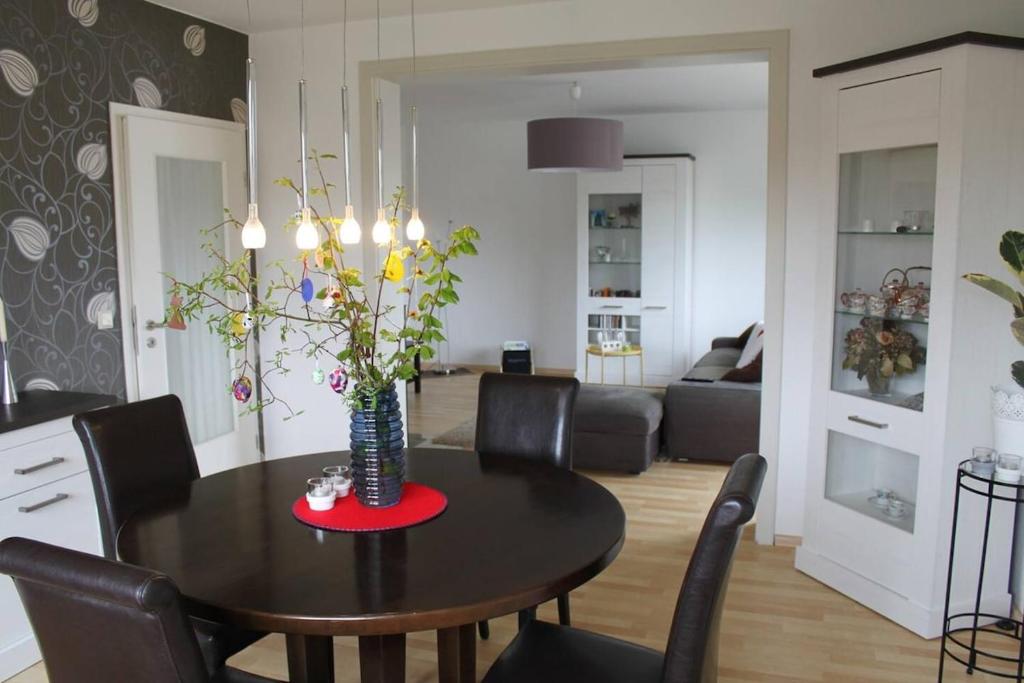 a dining room table with chairs and a vase with flowers at Modern feel-good apartment in Bad Lippspringe
