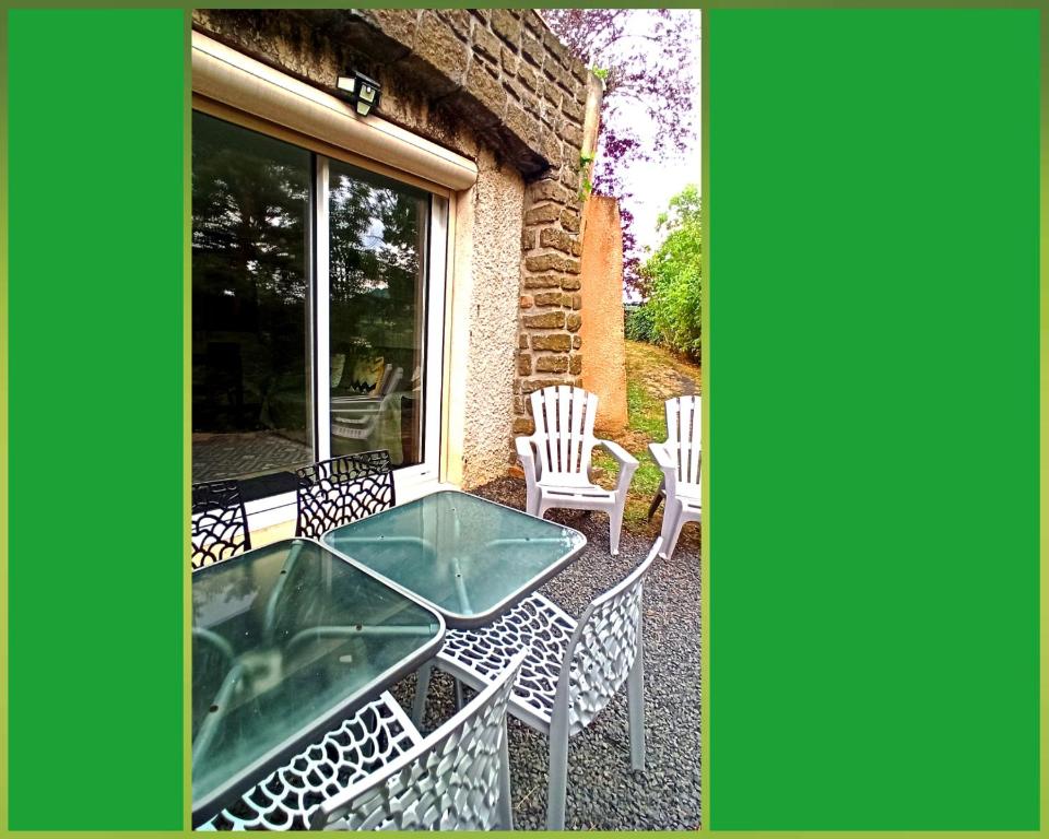 a patio with a glass table and chairs on a patio at Les Apparts du Vignal de Cheyrac in Polignac