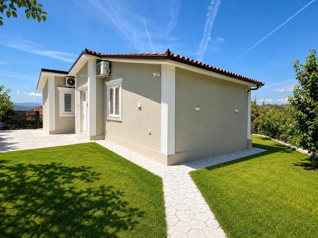 a small house with a green lawn in front of it at Vila Kordhaku in Petrelë