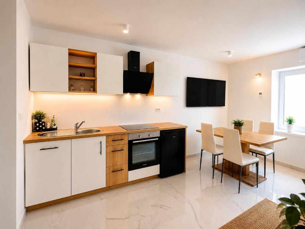 a kitchen with white cabinets and a table with chairs at Apartma 47 in Kobarid