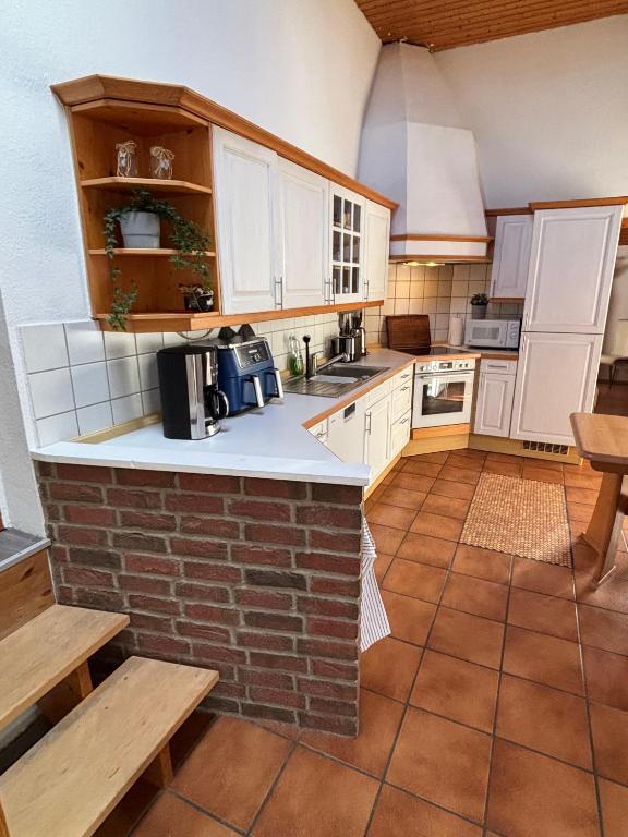 a kitchen with white cabinets and a brick wall at Ferienwohnung Frieda in Bückeburg
