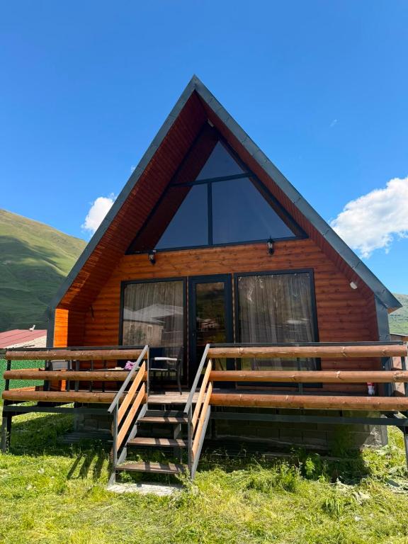 a log cabin with a large window and a porch at Tobani Cottage Kazbegi in Kazbegi