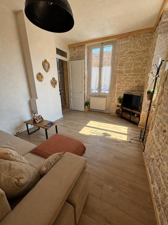 a living room with a couch and a tv at L'Écrin de Pierre - Gare & Centre à pied - Charme & Calme in Mâcon
