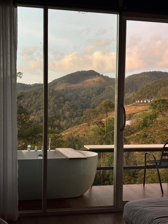 a bath tub in a room with a window at The will glamping&camping in Ban Na Pho