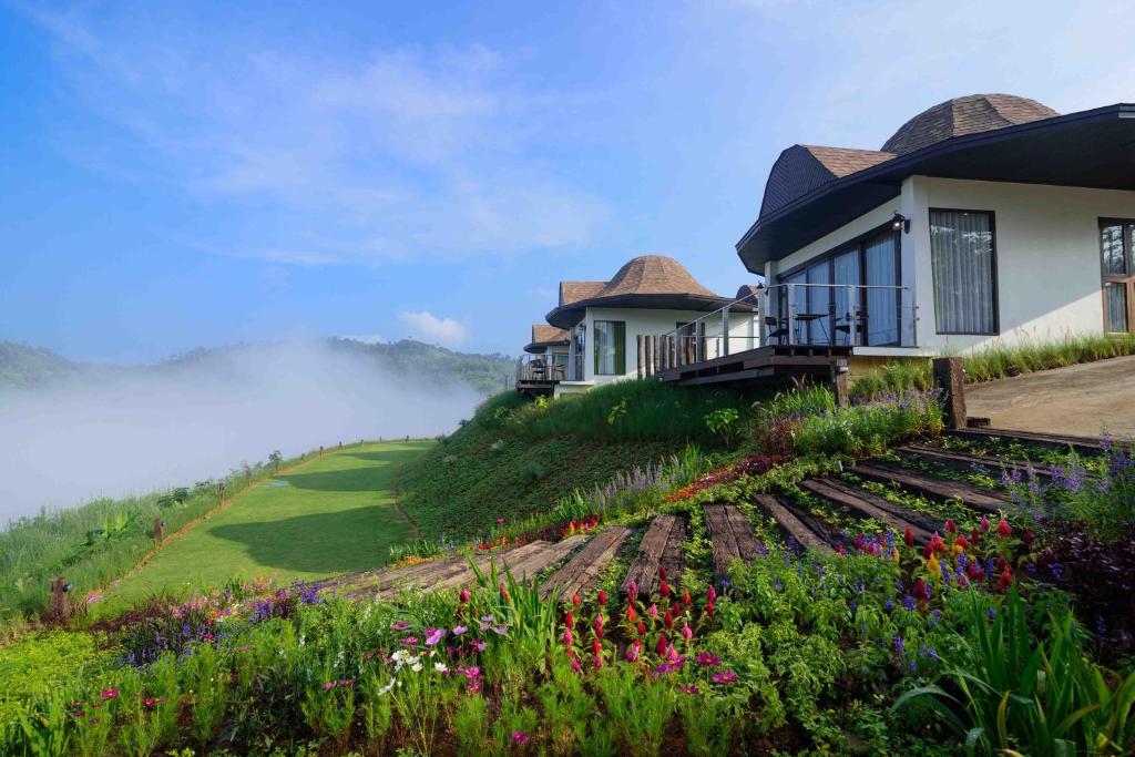 a house on top of a hill with flowers at At Tree Resort Khaokho in Khao Kho