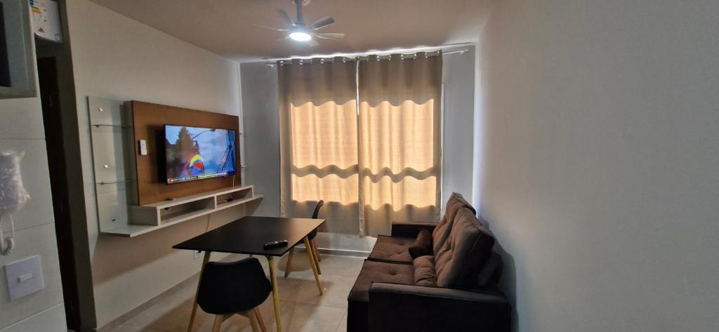 a living room with a couch and a table and a television at Apartamento Universitário in Uberaba