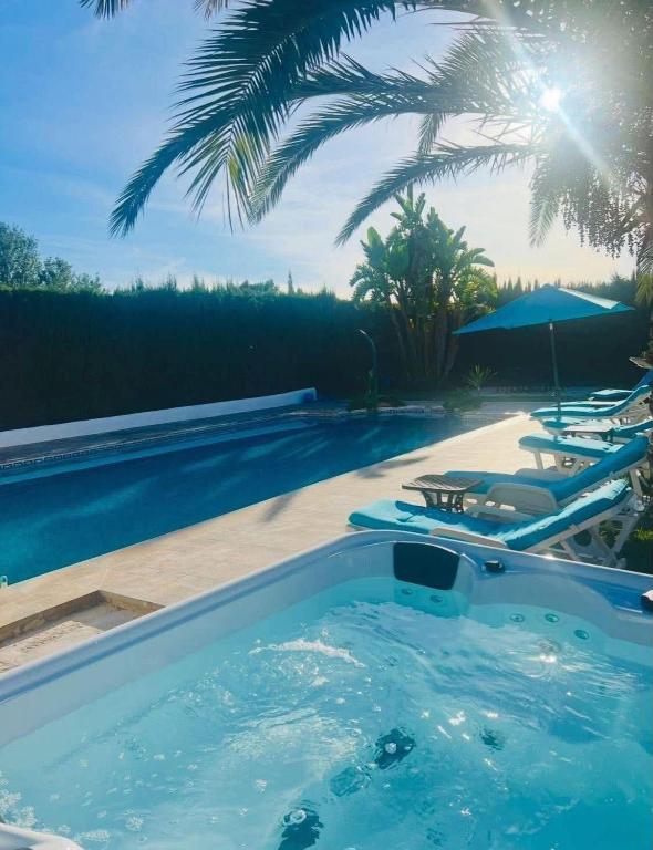 a swimming pool with a hot tub next to a resort at Chambre d'hôtes in Ondara