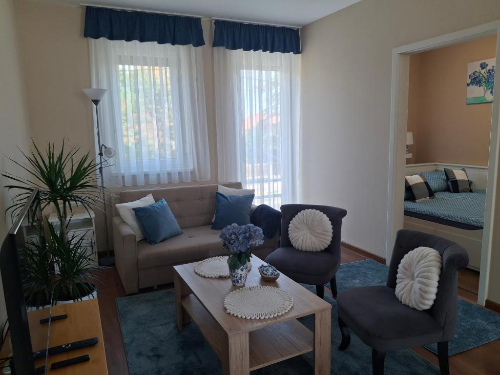 a living room with a couch and chairs and a table at Blue Iris Apartment in Kecskemét