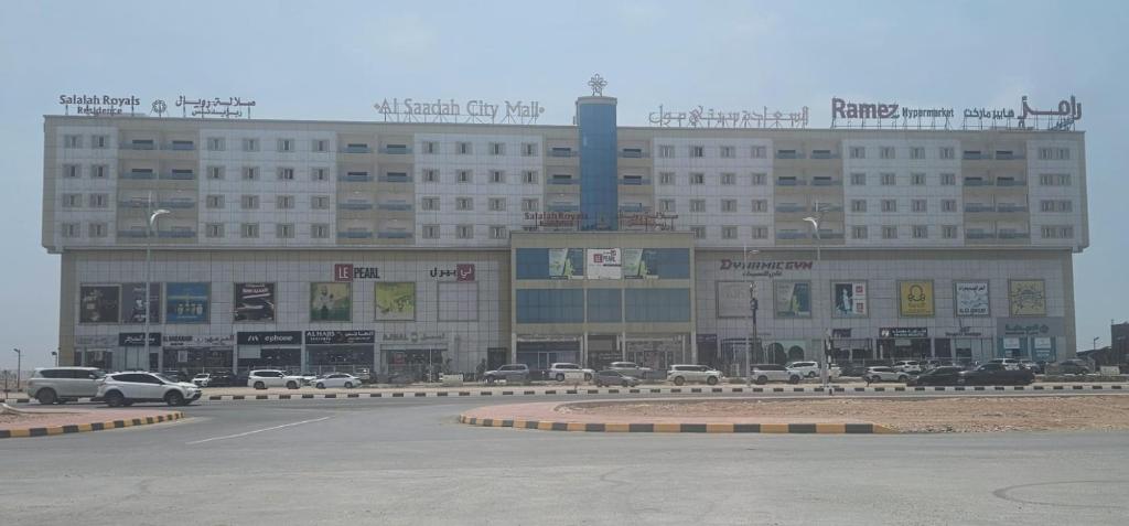a large building with cars parked in a parking lot at Salalah Royals Residence in Daḩārīz