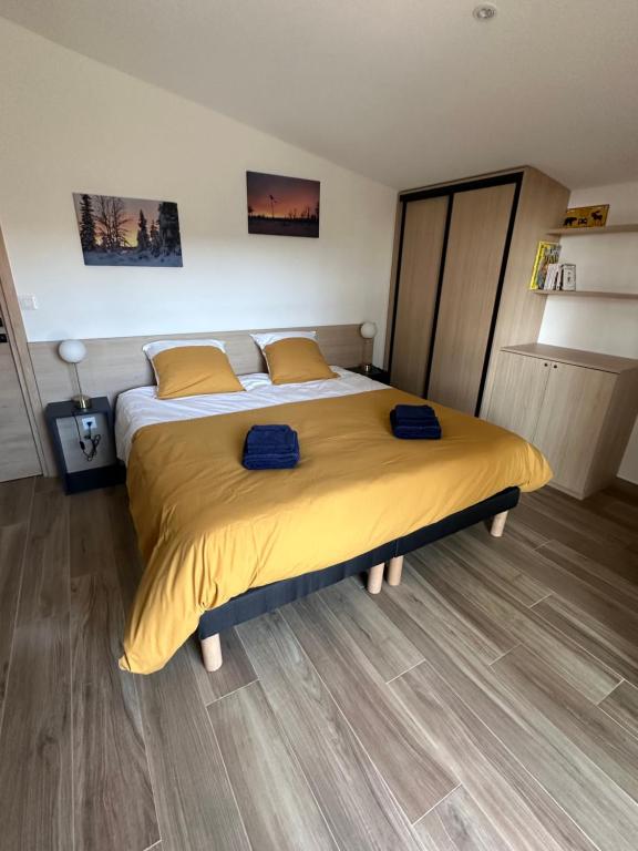 a bedroom with a large bed with yellow sheets at Appartement SUOMI in Saint-Sorlin-en-Bugey
