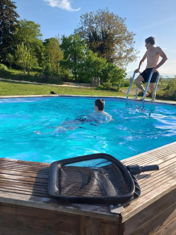 a man in a swimming pool with a man in the water at Gite Grand-Mère in Charron
