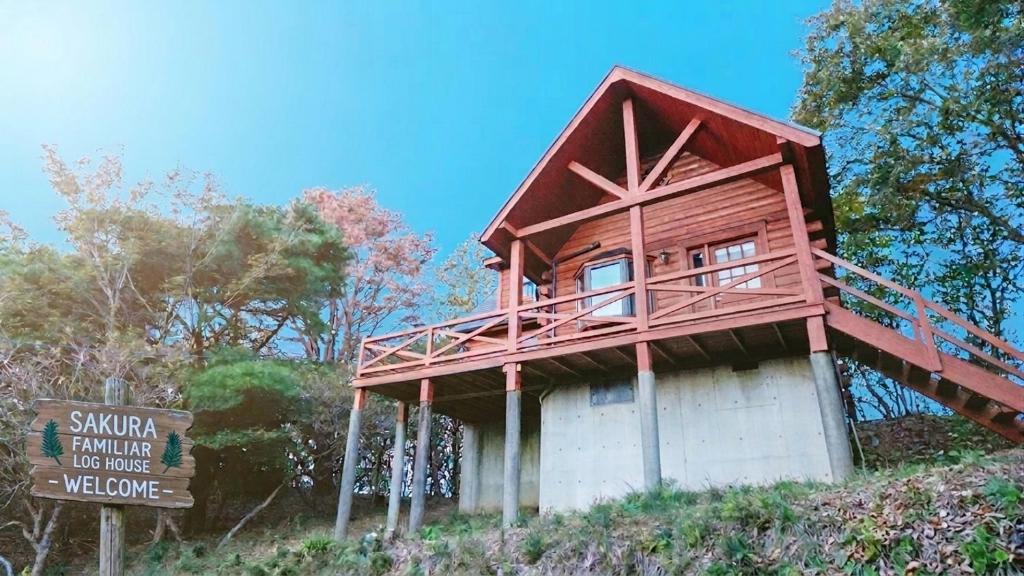 a small house on top of a hill with a sign at ログハウス SakuraFamiliar in Kawazu