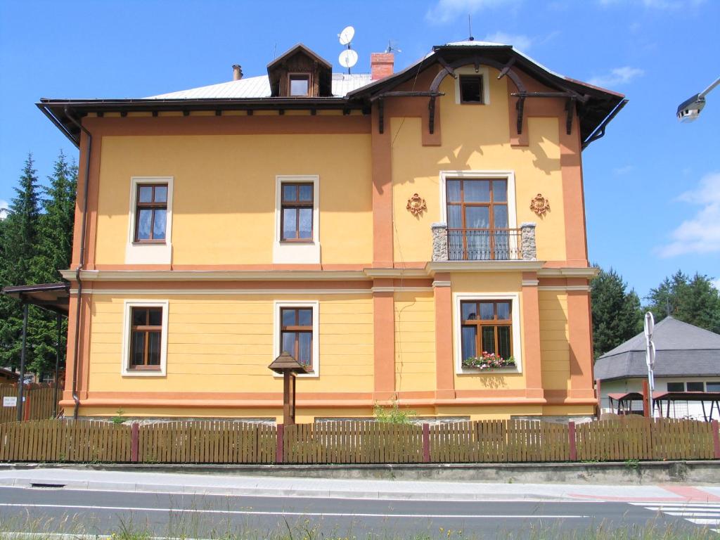 a yellow house with a fence in front of it at Penzion u Antošů in Jeseník