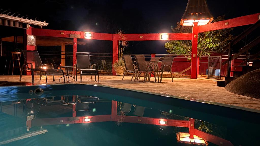 a swimming pool with chairs and a patio at night at Pousada Vila Taquaras in Balneário Camboriú