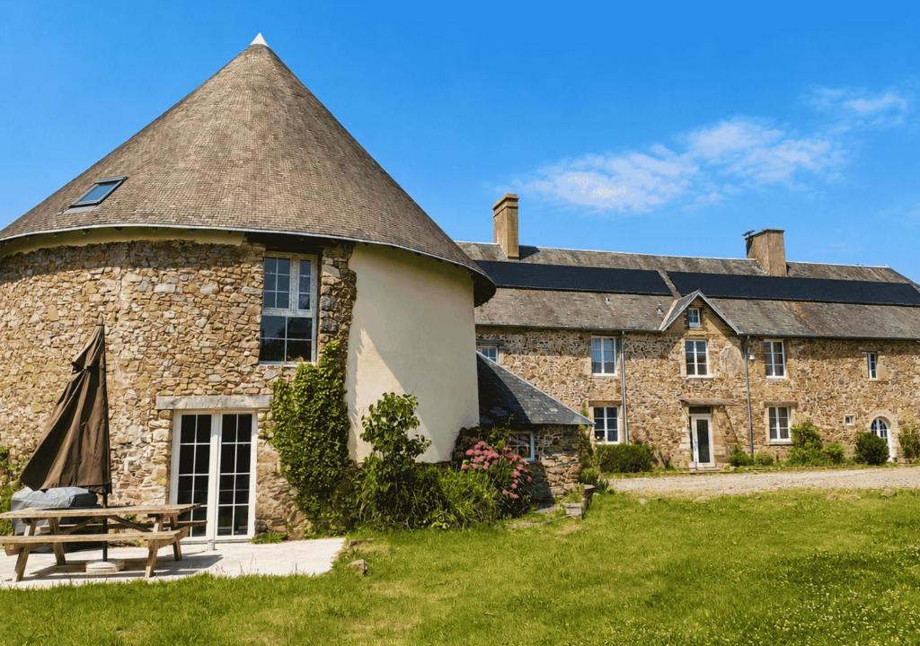a large stone building with a roof at La Synchronicité - Chambres d'Hôtes in Vaudrimesnil