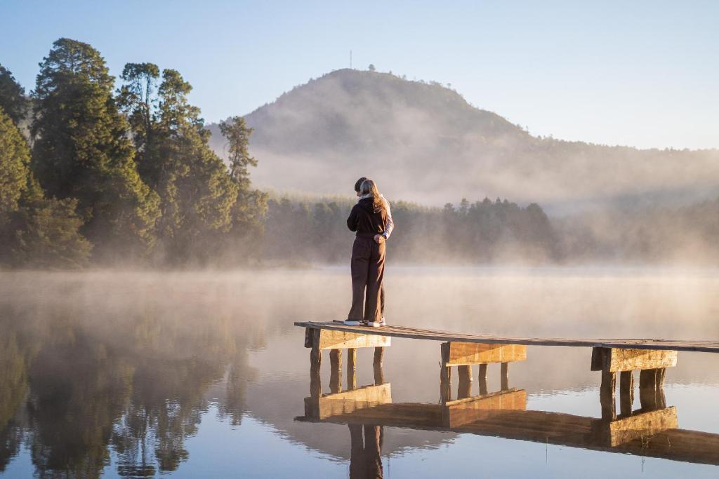 a person standing on a dock in the middle of a lake at Troutbeck Resort in Nyanga