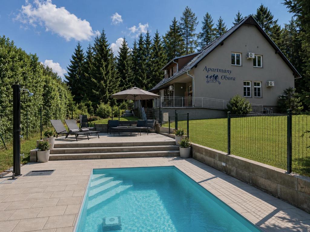 a swimming pool in front of a house at Apartmány Obora in Nová Bystřice