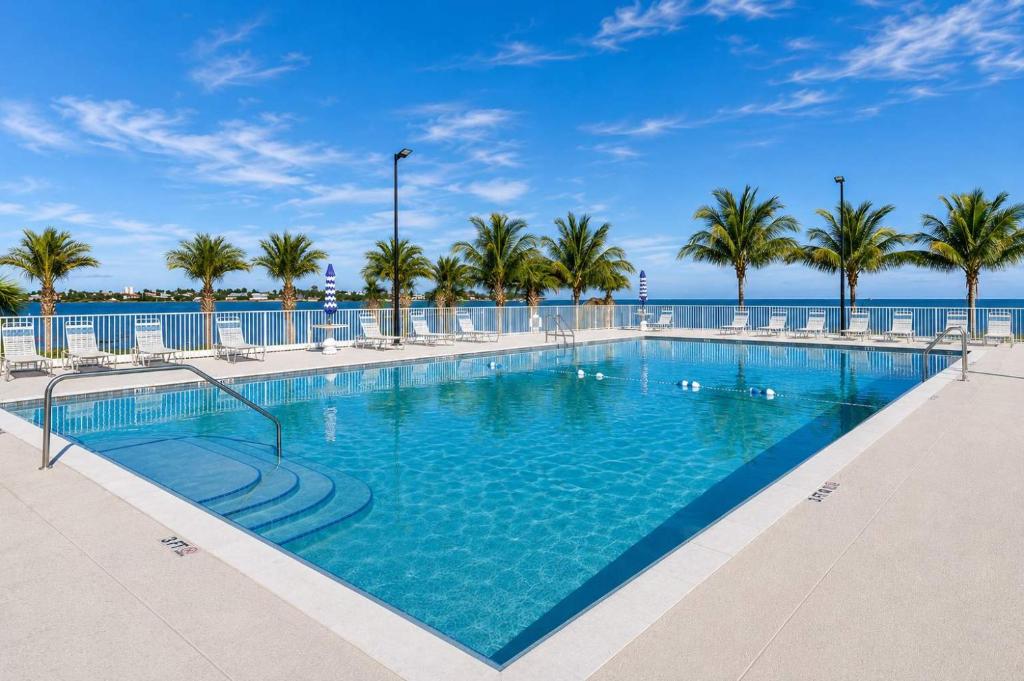 a large swimming pool with palm trees and the ocean at Keys Wade NEW 1B 2Bath in Marathon