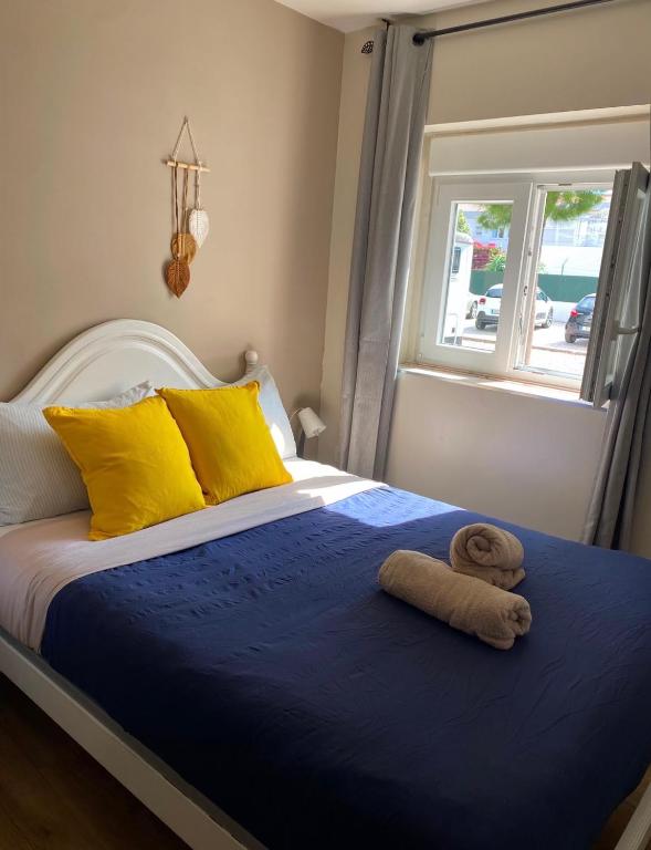 a bed with yellow and blue sheets and a towel on it at We Host Costa da Caparica in Costa da Caparica