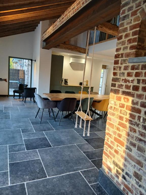 a room with a table and chairs and a brick wall at Aux charmes flamands in Wemaers-Cappel
