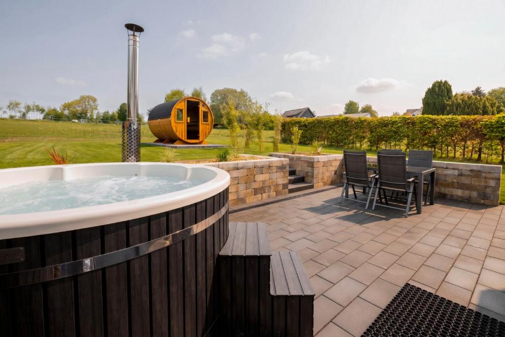 a hot tub on a patio with a table and chairs at Traumnest Eifel mit Sauna & Whirlpool in Monschau