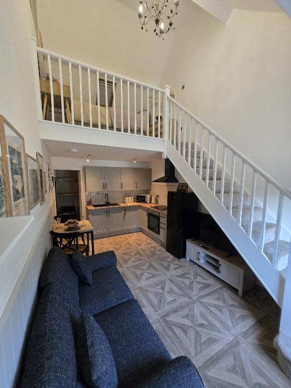 a living room with a couch and a staircase at Cosy Moat House Cottage #2 in Pembroke