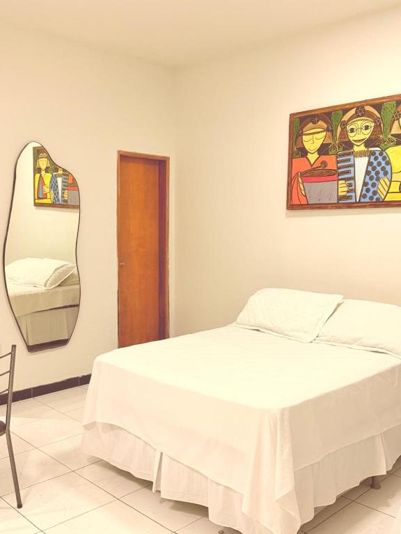 a bedroom with a white bed and a mirror at AP 06 - Apartamento Estudio completo in Balsas