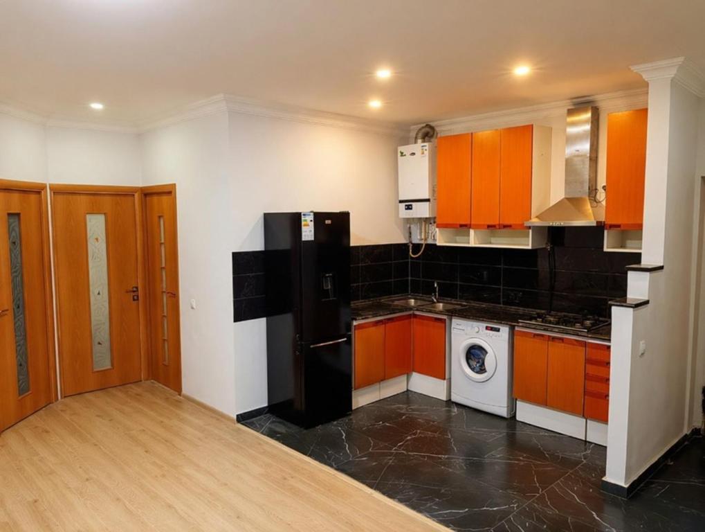 a kitchen with orange cabinets and a black refrigerator at Relax garden area with BBQ zone in Yerevan