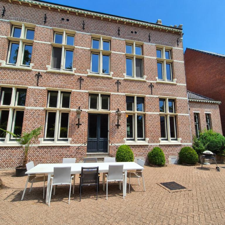a table and chairs in front of a brick building at Spacious manor house with pool & playground in Essen