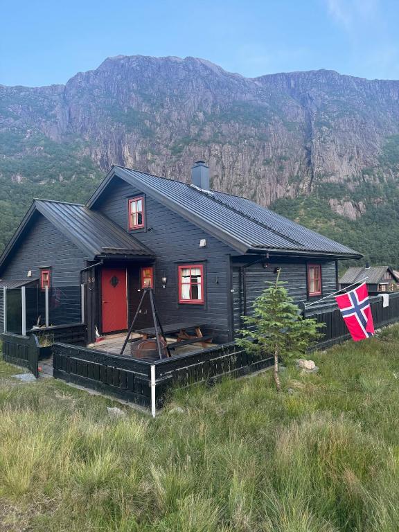 a black house with a red door on a hill at Lyngbu på Stavtjørn in Vikeså
