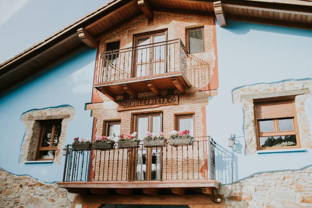 a building with a balcony with flowers on it at Casa Rural Ecológica Arrizurieta in Bermeo