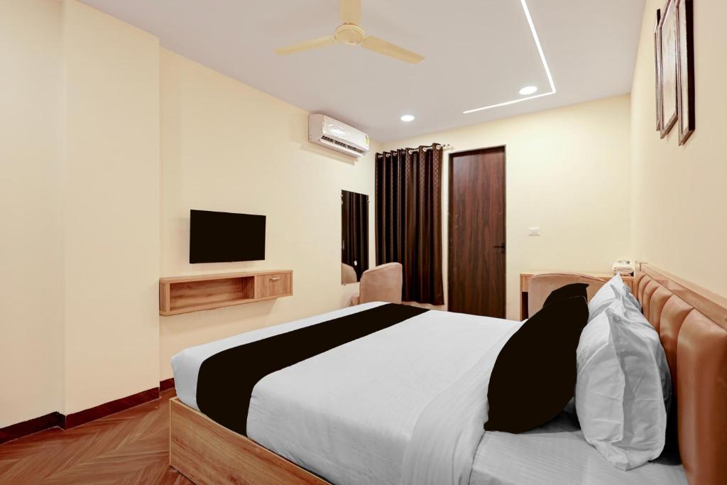 a bedroom with a bed and a tv on the wall at Hotel O Grand Shivay in Indore