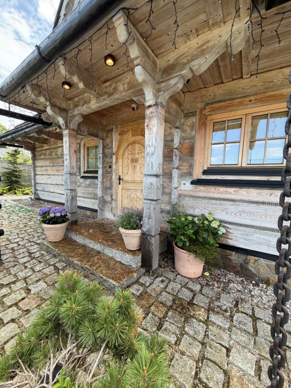 a house with a porch with potted plants in front of it at Tatra Whisper Chalet in Ząb