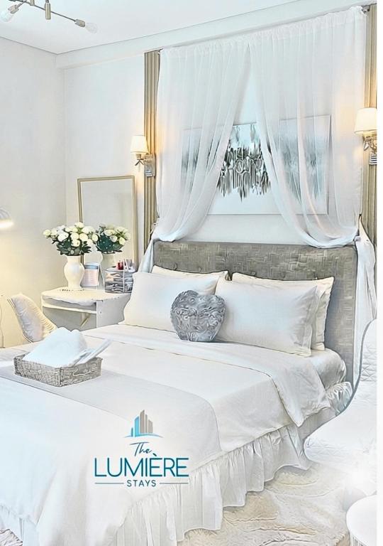 a white bedroom with a large bed with white curtains at The Lumière Stays Cozy Mallside Boutique Haven in Trece Martires