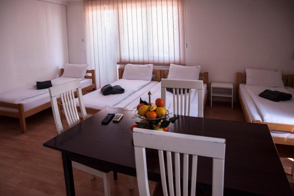 a room with three beds and a table and chairs at Modex Apartments in Paraćin